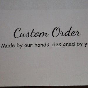 May include: A white card with the words "Custom Order" in elegant script. Below, the text reads "Made by our hands, designed by you" in a simple, easy-to-read font. The overall design suggests a personalized service.
