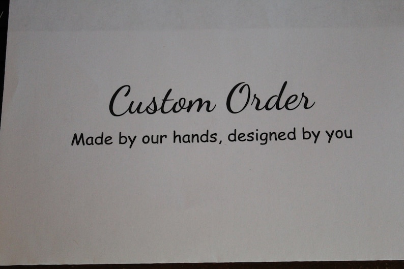 May include: A white card with the words "Custom Order" in elegant script. Below, the text reads "Made by our hands, designed by you" in a simple, easy-to-read font. The overall design suggests a personalized service.