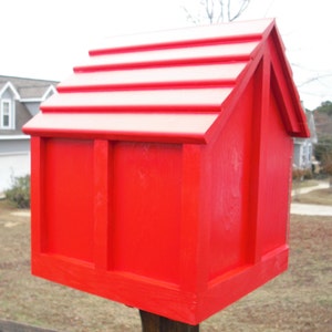 May include: A bright red wooden birdhouse with a gabled roof and a simple design. The birdhouse is mounted on a wooden post.