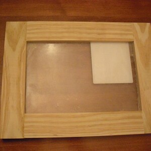 May include: A wooden picture frame with a clear glass insert and a white mat. The frame has a natural wood finish and is ready to display a photo or artwork.