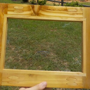 May include: A wooden picture frame with a clear glass insert. The frame is made of light wood with a natural finish. The frame is approximately 12 inches by 16 inches.