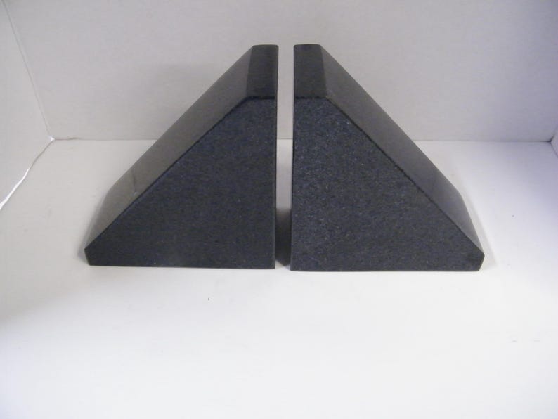 Puede incluir: Dos sujetalibros de granito gris oscuro. Cada sujetalibros tiene forma de tri&aacute;ngulo rect&aacute;ngulo con base plana y borde vertical. El granito tiene una textura moteada. Los sujetalibros est&aacute;n dise&ntilde;ados para sujetar libros en posici&oacute;n vertical.