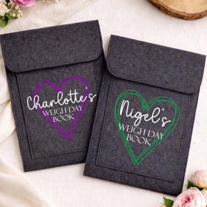 May include: Two dark grey felt pouches with a flap closure. One pouch has a purple heart design with the text "Charlotte's WEIGH DAY BOOK". The other has a green heart design with the text "Nigel's WEIGH DAY BOOK".