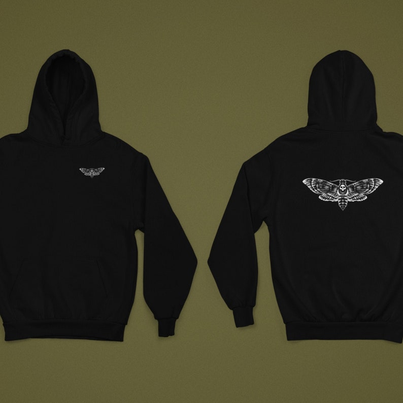 Puede incluir: Sudadera con capucha negra con un dise&ntilde;o de polilla blanca en la parte delantera y trasera. La parte delantera presenta un peque&ntilde;o gr&aacute;fico de polilla, mientras que la parte trasera muestra una polilla m&aacute;s grande con un dise&ntilde;o de calavera. La sudadera tiene capucha y mangas largas.