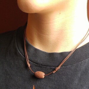May include: A brown leather cord necklace with a brown lava rock bead.