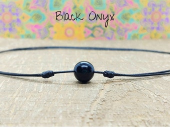 May include: A black onyx bead necklace with a black cord. The necklace is tied with a knot on each end.