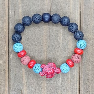 May include: A black lava rock bracelet with red, blue and brown beads and a red turtle charm.