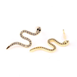 May include: A pair of gold snake earrings with clear and black cubic zirconia stones.