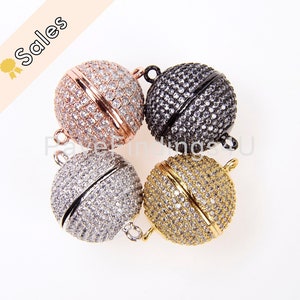 May include: Four round magnetic clasps for jewelry making. The clasps are made of metal and have a pave setting of clear rhinestones. The clasps are shown in four different colors: rose gold, silver, black, and gold.