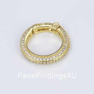 May include: Gold-toned hoop earrings with a pave setting of clear cubic zirconia stones. The earrings have a hinged clasp.