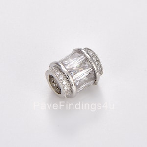 May include: A silver-toned spacer bead with a clear rectangular crystal in the centre. The bead is surrounded by smaller clear crystals.