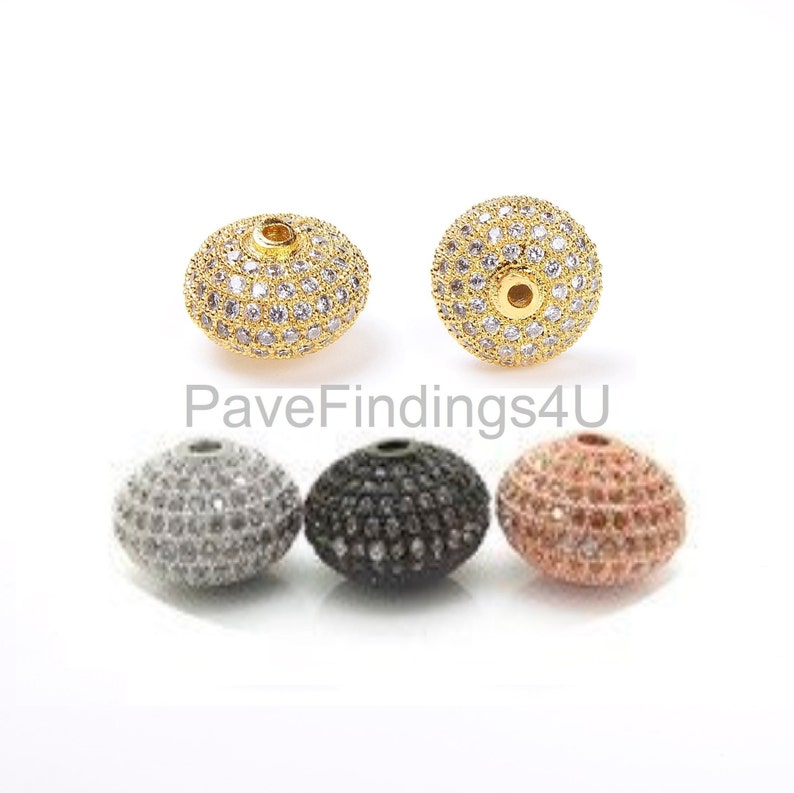 May include: Five round beads with a pave setting of clear cubic zirconia stones. The beads are in gold, silver, black, and rose gold.