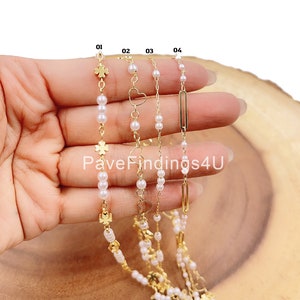 May include: Four gold chains with different charms, including a clover, heart, and rectangle, are layered on top of each other. The chains are strung with small white pearls. The chains are labeled 01, 02, 03, and 04.