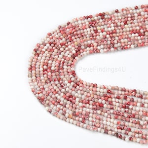 May include: A strand of red and white gemstone beads. The beads are faceted and have a speckled appearance. The beads are approximately 4mm in diameter.