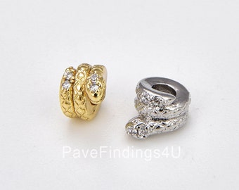 May include: Two snake charm beads, one gold and one silver, with clear crystal accents. The beads are designed to be used on a bracelet or necklace.