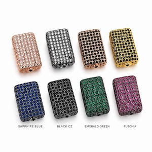 May include: Eight rectangular beads arranged in two rows, each encrusted with small cubic zirconia stones. The colors include clear, black, and rose gold, gold, blue, green, and fuchsia tones. Each bead features a single circular hole at the base.