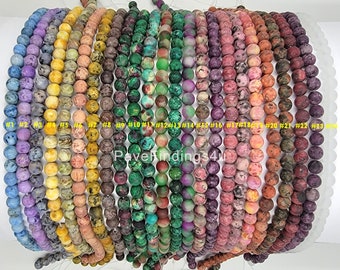 May include: A collection of round gemstone beads in various colors, including purple, yellow, green, red, and brown. Each strand is labeled with a number. The beads are strung together, ready for jewelry making. The text "PaveFindings4u" is visible.
