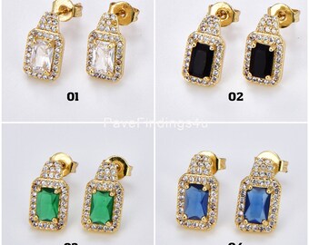 May include: Four pairs of gold earrings with a square-shaped stone in the center. The stones are white, black, green, and blue. Each earring has a small, clear stone around the perimeter of the square stone.