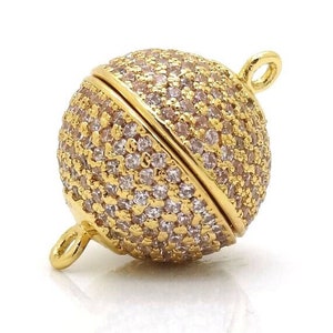 May include: Gold-toned magnetic clasp with a round, faceted design. The clasp is covered in small, clear rhinestones.