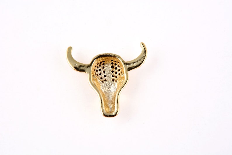 May include: Gold-toned bull head pendant with a detailed design. The pendant is hollow and has a textured surface.