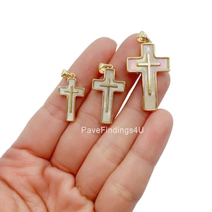 Peut inclure: Trois pendentifs en forme de croix dorés avec incrustation de nacre blanche. Les croix sont de tailles différentes et sont disposées en rangée du plus grand au plus petit.