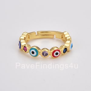 May include: Gold adjustable ring with a row of colorful evil eye charms. Each charm has a white center and a blue, red, or turquoise outer ring. The ring is accented with small clear, purple, and blue gemstones.