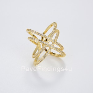 May include: Gold ring with a criss-cross design, featuring small clear stones.