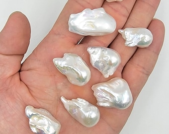 May include: A collection of eight white baroque pearls of varying sizes and shapes. The pearls have an iridescent sheen and are displayed on a hand.