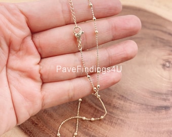 May include: A gold chain necklace with small round beads. The chain is delicate and has a lobster clasp.