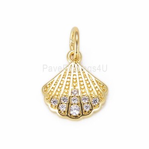 May include: Gold seashell charm with clear cubic zirconia stones. The charm has a detailed design and is perfect for adding a touch of elegance to jewelry.