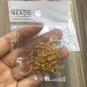 May include: A clear plastic bag filled with gold jump rings. The bag has a white label with the text "BEADS CREATION4U" printed on it.