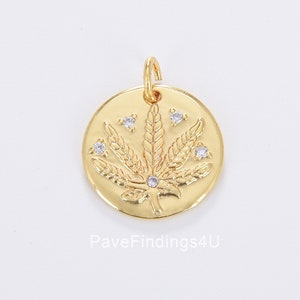 Puede incluir: Encanto de colgante de tono dorado con un diseño detallado de hoja de marihuana con piedras de circonita cúbica transparentes.