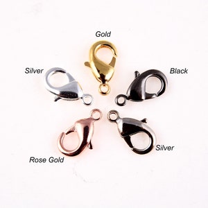 May include: Five lobster claw clasps in different colors: gold, silver, black, rose gold, and silver. The clasps are arranged in a circle on a white background.