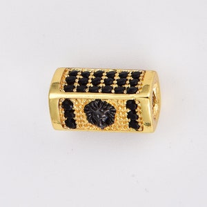 May include: Gold-toned bead with a black lion head design and black cubic zirconia stones.