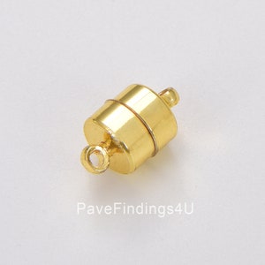 May include: A gold-colored magnetic clasp, cylindrical in shape, with a small loop on each end. The clasp is designed for jewelry making and features a smooth, polished finish. The image is taken from a slightly elevated angle.
