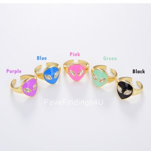 May include: Adjustable gold-tone rings featuring alien face designs in purple, blue, pink, green, and black enamel. Each ring has a gold band and two clear, oval-shaped crystal eyes. The text "PaveFindings4U" is visible.