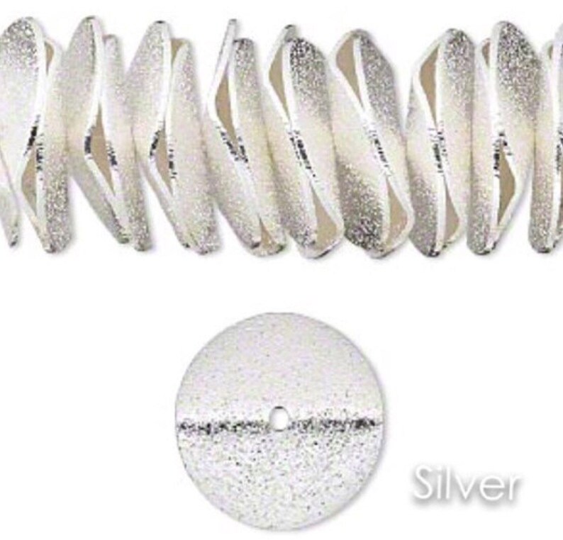 May include: Silver-toned metal beads with a textured surface. The beads are shaped like small, flat discs with a hole in the center. The beads are arranged in a row, and the word "Silver" is printed below the beads.