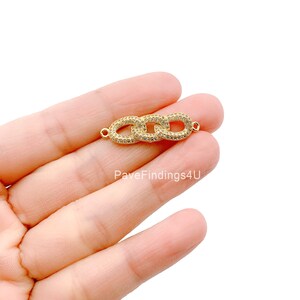 May include: A gold-colored chain link connector with three oval links, each encrusted with small, clear crystals. The connector has small loops on each end for attachment. The text "PaveFindings4U" is visible in the image.