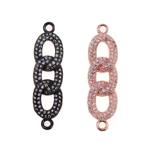 May include: Two decorative jewelry chain links. One is black with clear stones, the other is rose gold with clear stones. Each link has three oval-shaped links connected together. Each link has a small loop at the top and bottom.