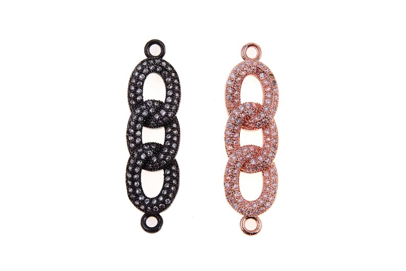 May include: Two decorative jewelry chain links. One is black with clear stones, the other is rose gold with clear stones. Each link has three oval-shaped links connected together. Each link has a small loop at the top and bottom.