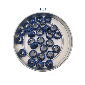 May include: A close-up of a silver bowl filled with blue spacer beads. The beads are round and have a small hole in the center. The beads are covered in small blue crystals.