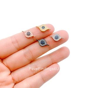 May include: Four evil eye charms with a blue center and clear crystal accents. The charms are in gold, rose gold, silver, and black.