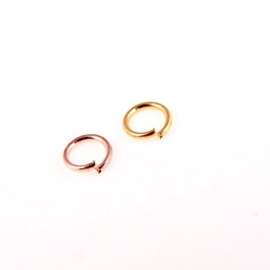 May include: Two jump rings, one gold and one rose gold, on a white background.