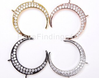 Puede incluir: Cuatro colgantes de media luna en oro, oro rosa, plata y negro. Cada colgante está incrustado con pequeños cristales transparentes. Los colgantes tienen pequeños bucles para sujetarlos a diseños de joyería. Sobre un fondo blanco.