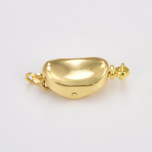 May include: Gold-toned clasp for a necklace or bracelet. The clasp is shaped like a half-circle and has a small, round latch.