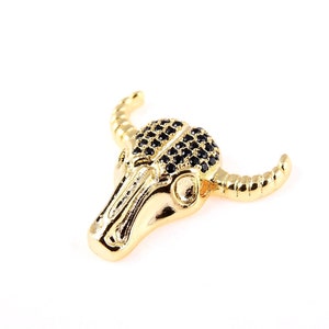 May include: Gold-tone bull skull pendant with black crystal accents.