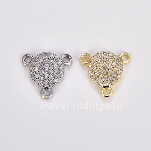 May include: Two round, pave-set connector charms with three jump rings. One charm is silver and the other is gold.