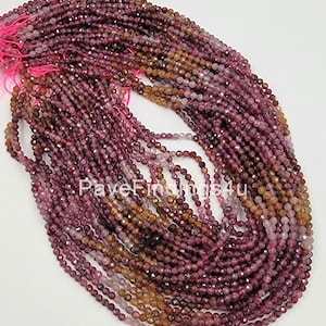 May include: A strand of approximately 200 small, faceted, reddish-brown gemstone beads. The beads are about 3mm in diameter and have a slightly irregular shape. The beads are strung on a thin, pink thread.