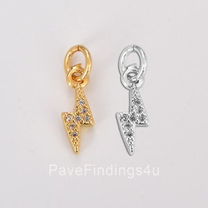 May include: Two lightning bolt charms, one gold and one silver, with clear crystal accents.  The charms have a jump ring for attaching to a bracelet or necklace.