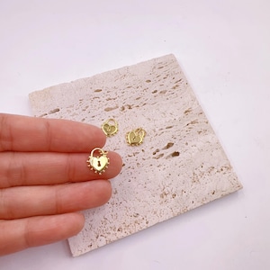 May include: Three gold heart-shaped lock charms with a keyhole detail. The charms have a textured edge and are perfect for adding a touch of whimsy to jewellery.